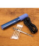 Der Puffco Pivot in der Sapphire Edition in blau liegt auf einem Holztisch. Davor liegen Wattestäbchen, ein Dabtool aus Edelstahl und das USB-C Ladekabel.