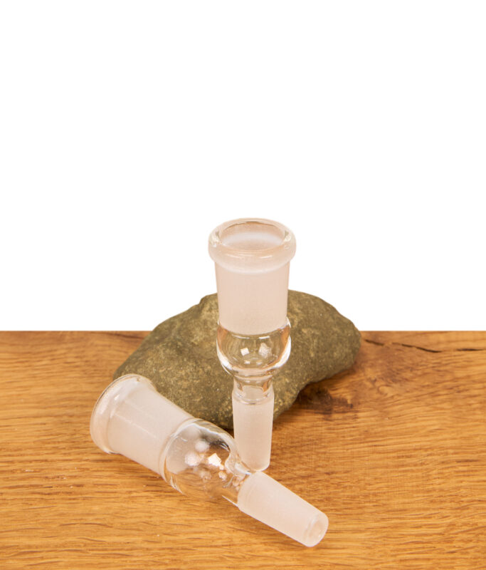 Zwei gläserne Bongadapter NS10 auf NS14 Erweiterungen auf einer Holzfläche; ein Adapter steht aufrecht vor einem Deko-Naturstein, der andere liegt horizontal davor.