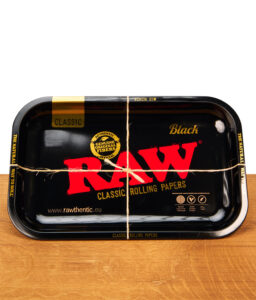 Schwarze RAW Black Classic Rolling Tray Drehunterlage aus Metall mit rotem Logo, mit einer Paketschnur kreuzweise verschnürt.