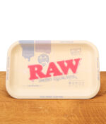 RAW Dab Rolling Tray mit halbtransparentem Silikonschutz auf einem Holztisch. Das klassische RAW-Logo scheint durch.
