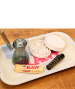 RAW Dab Rolling Tray mit Silikonschutz in Benutzung, bestückt mit Glas-Bubbler, Hanf-Grinder, Clipper und RAW Tips.