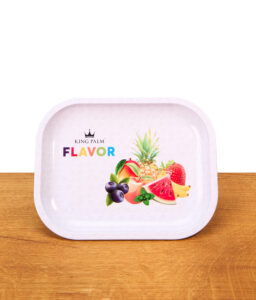 King Palm Rolling Tray Flavor Mini aus Metall auf einem Holztisch. Weißes Drehtablett mit erhöhtem Rand, bunter Fruchtgrafik und Logo.