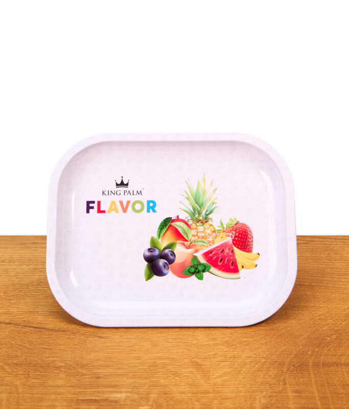 King Palm Rolling Tray Flavor Mini aus Metall auf einem Holztisch. Weißes Drehtablett mit erhöhtem Rand, bunter Fruchtgrafik und Logo.
