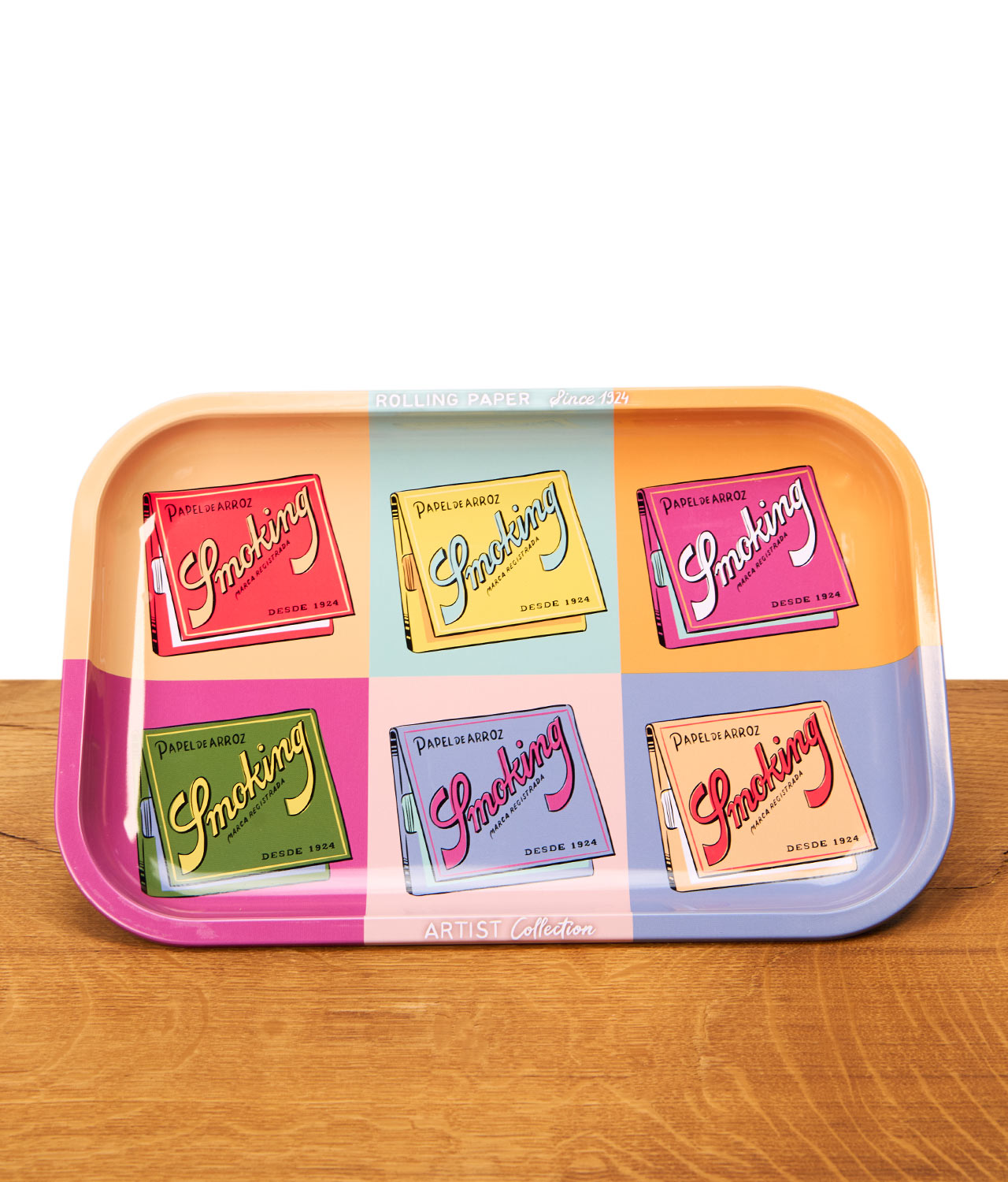 smoking-rolling-tray-artist-collection-jpg Smoking Rolling Tray Artist Collection aus Metall mit sechs bunten Retro-Motiven von Smoking-Blättchen im Pop-Art-Stil auf einem Holztisch.