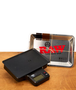 Schwarze digitale RAW Tray Scale Waage neben dem passenden RAW Metall-Tray auf einem Holztisch.