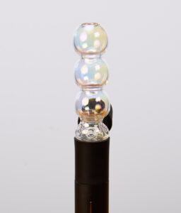 Schimmernder Puffco Pivot Bubble Top Iridescent aus Glas. Der kugelförmige Aufsatz ist passgenau auf den schwarzen Vaporizer aufgesteckt.