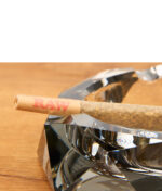 Handgedrehter Joint mit RAW-Filter liegt in der Einkerbung des RAW Dark Side Kristallglas-Aschenbechers.