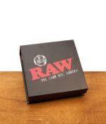 Geschlossene schwarze Geschenkverpackung des RAW The Dark Side Kristallglas-Aschenbechers auf Holzoberfläche.