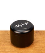Geschlossener Stayhigh Puck Large aus mattschwarzem Aluminium mit Logo-Aufdruck auf einer Holzoberfläche.