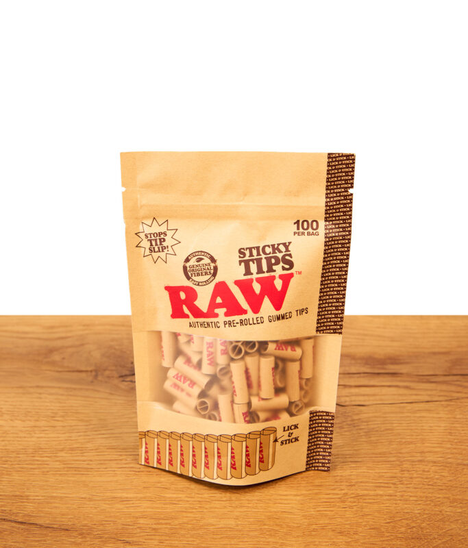 RAW Sticky Tips 100er Pack: Vorgedrehte, ungebleichte Filtertips mit Klebestreifen im Standbeutel auf Holz.