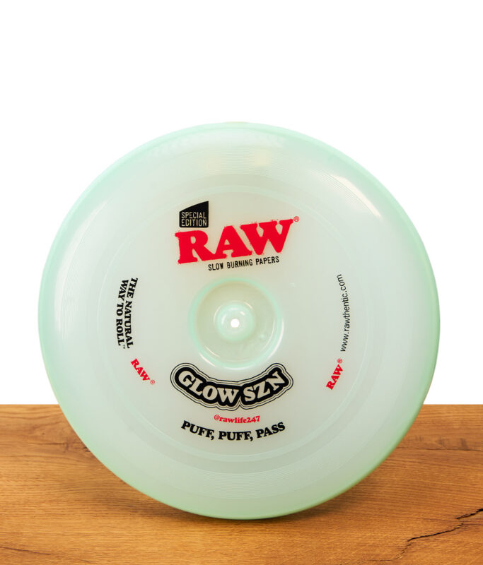 RAW Frisbee Cyan Glow SZN Special Edition: Runde, mintgrüne Kunststoff-Frisbee und Rolling Tray auf einer Holzoberfläche.