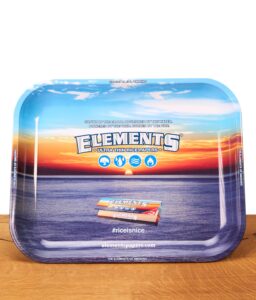 Rechteckiges Elements Rolling Tray aus Metall auf einem Holztisch. Die Drehunterlage zeigt ein Ozean-Sonnenuntergang-Motiv mit Markenlogo.