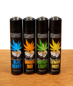 Clipper HomeGrown 4er-Set wiederbefüllbare Reibradfeuerzeuge in Schwarz mit bunten Hanfblatt-Motiven bekannter Cannabis-Sorten auf Holz.