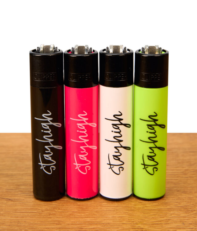 Clipper Stayhigh 4er-Set wiederbefüllbare Reibradfeuerzeuge in Schwarz, Pink, Weiß und Neongrün mit geschwungenem Schriftzug auf Holz.