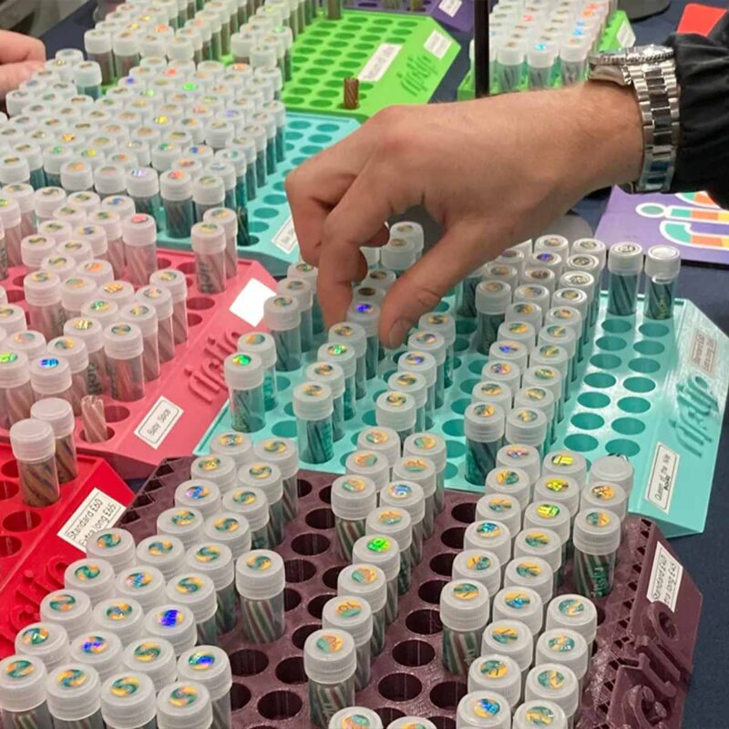 Hand greift nach RipTip Glasfiltern in großen Displays mit dutzenden ausgestellten Filtern. Wahrscheinlich auf einer Messe.