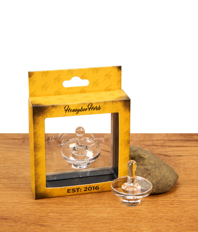 Honeybee Herb Terp Slurper Carb Cap neben der gelben Originalverpackung auf Holz.