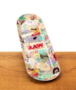 RAW x Chris Psiacik Skate Deck Rolling Tray auf Holzoberfläche, buntes Dreh-Tablett aus Metall in Skateboard-Form.
