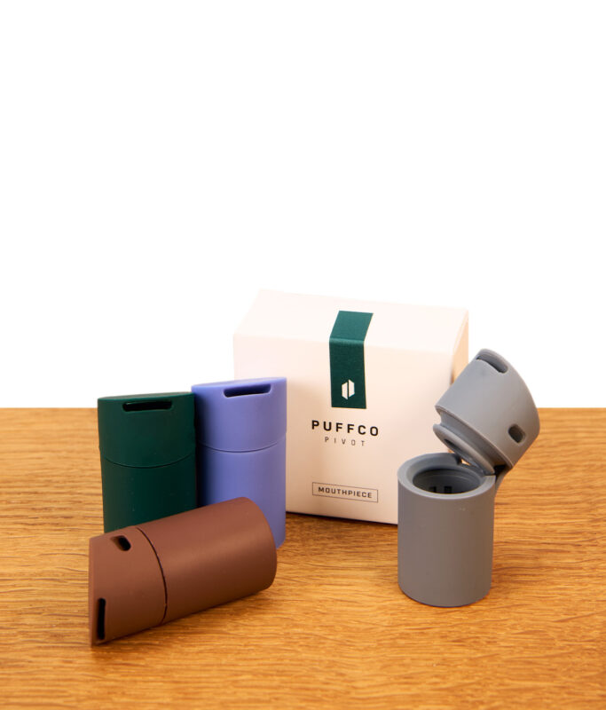 Puffco Pivot Mundstück Set in vier Farben samt Originalverpackung auf Holz dekoriert, das graue Silikonteil ist geöffnet.