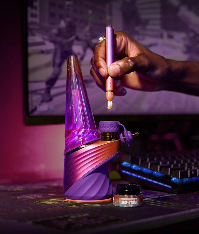 Das Peak Pro Plasma E-Rig neben einem Glasbehälter beim Laden eines Dabs per Hot Knife in passender Edition