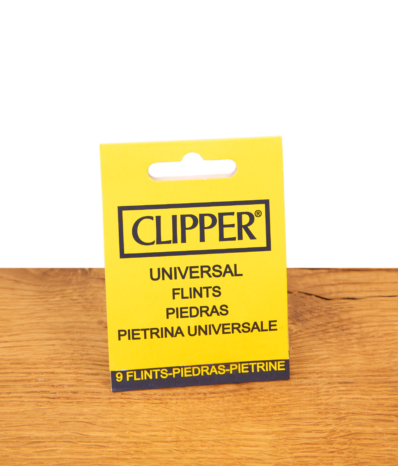 clipper-universal-feuersteine-9er-pack-jpg Gelbe Verpackung der Clipper Universal Feuersteine im 9er Pack stehend auf einer hellen Holzoberfläche.