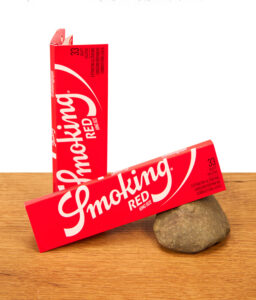 Zwei rote Packungen Smoking Red King Size Blättchen auf einer Holzoberfläche