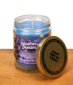 Geöffnete Smoke Odor Duftkerze Blueberry Dreamz auf Holz. Anti-Geruch Kerze mit blauem Wachs und angelehntem Metalldeckel.