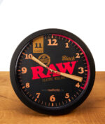 Frontansicht der RAW Black Stash Clock auf Holz. Funktionierende Versteckuhr im RAW-Design mit auffälligen, konischen Joint-Zeigern.