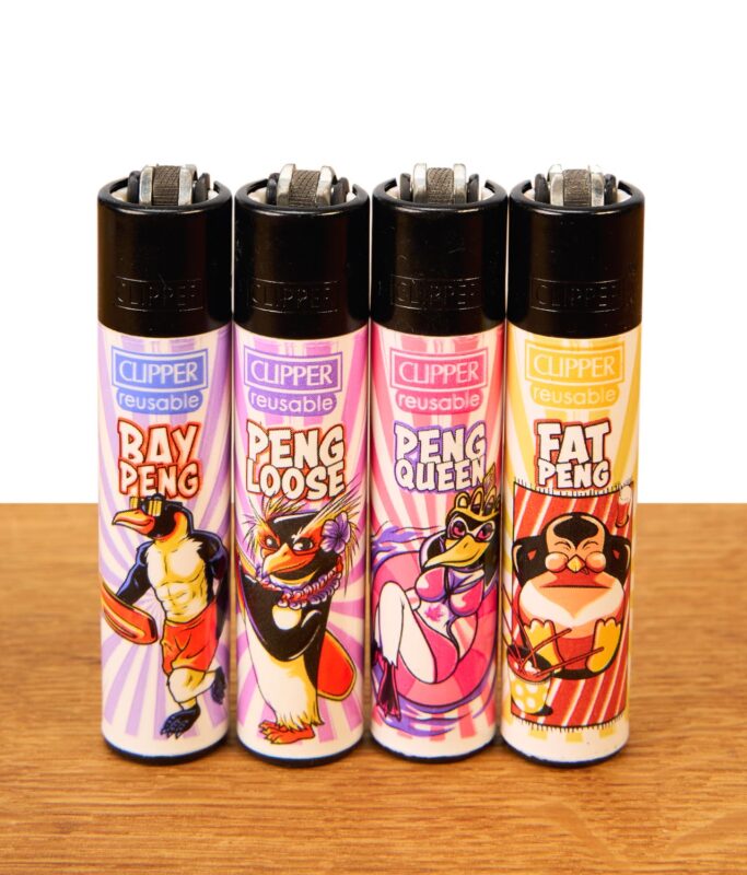 Clipper Penguin 4er Serie. Vier nachfüllbare Feuerzeuge auf Holz mit bunten Comic-Pinguin-Motiven und Metall-Zündrad.