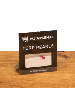 MJ Arsenal Ruby Terp Pearls im 2er-Pack (4mm) in der schwarzen Originalverpackung, präsentiert auf einer Holzoberfläche mit einem Stützstein.