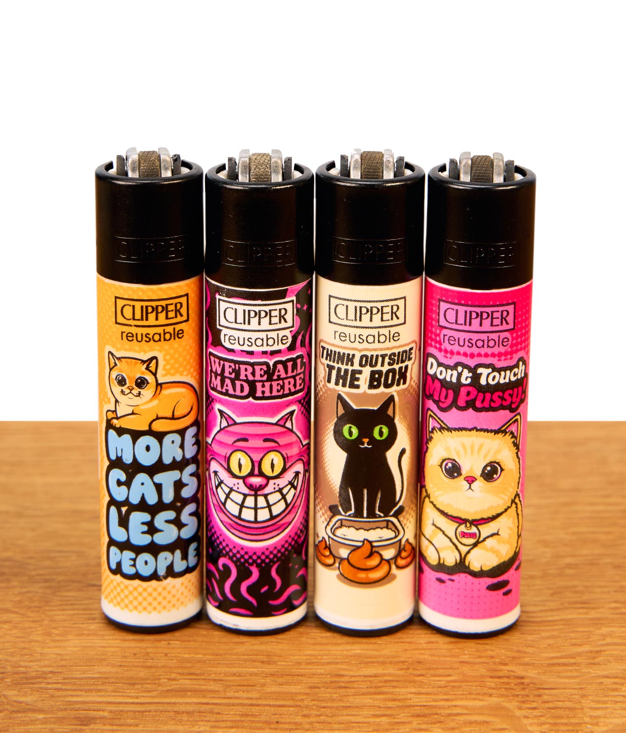 clipper-catz-4-4er-serie-jpg Nachfüllbares Clipper Feuerzeug 4er-Set Catz #4 mit bunten Katzenmotiven und Zündstein auf Holztisch.