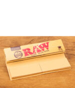 Geöffnetes RAW Connoisseur King Size Slim Heftchen mit integrierten Filtertips auf Holzoberfläche.